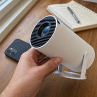 Tamaño real del mini proyector en la mano, comparado con un móvil