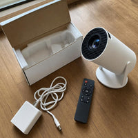 Contenido de la caja del mini proyector: mando, cargador y proyector